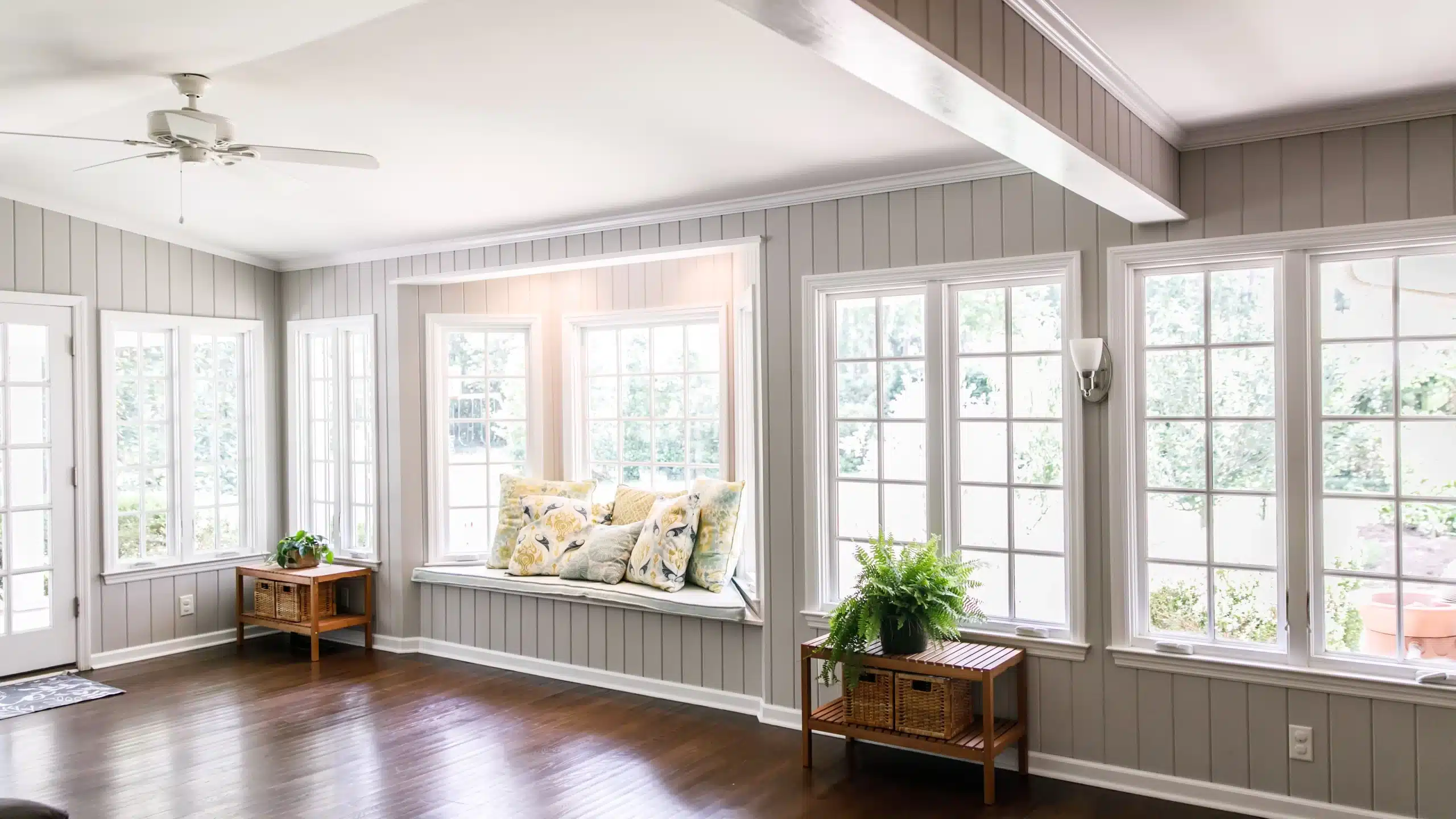 A sitting room with a wall of new windows and hardwood floors