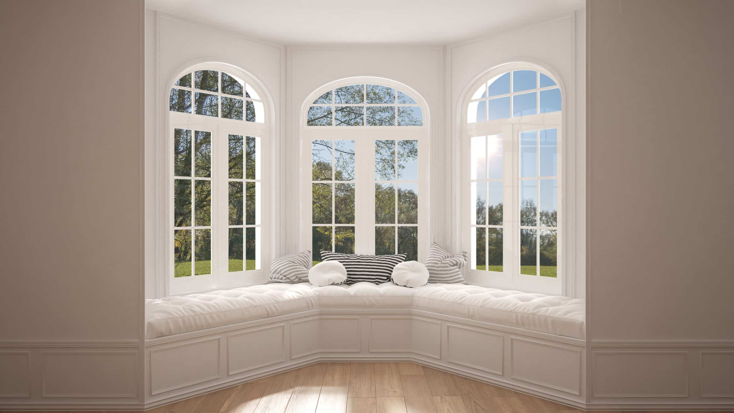 A bay window with reading nook all in light colors and trees out the windows